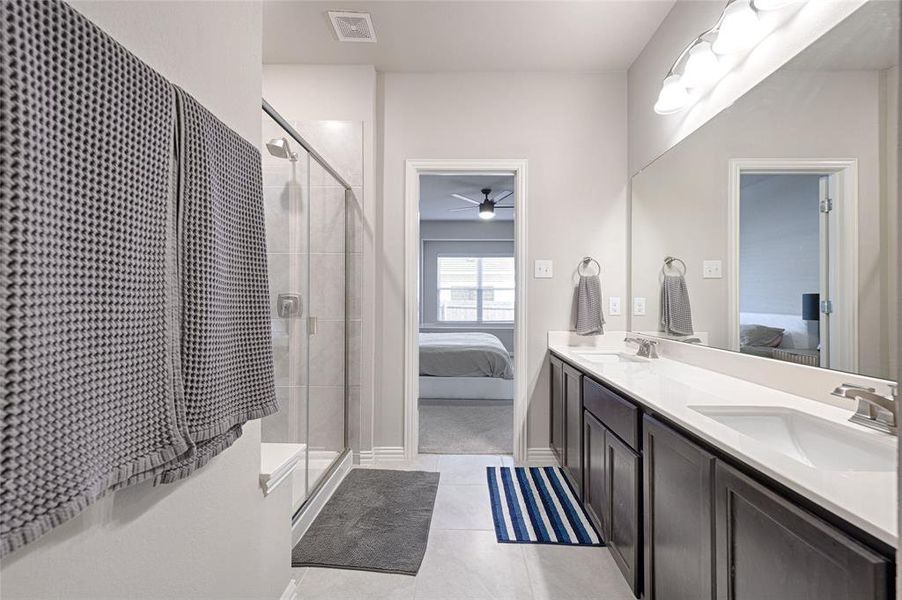 Primary ensuite bathroom with double sinks and stained vanity cabinets