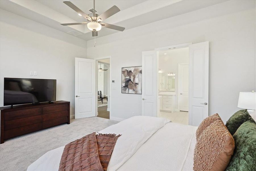 Bedroom with ceiling fan, light colored carpet, and ensuite bath