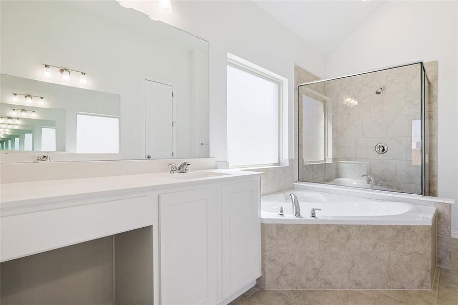 Bathroom with independent shower and bath, vanity, lofted ceiling, and tile patterned flooring