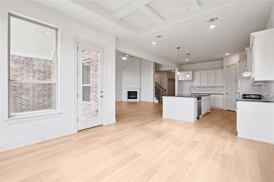 Kitchen featuring dishwasher, a kitchen island with sink, light wood-type flooring, white cabinets, and pendant lighting