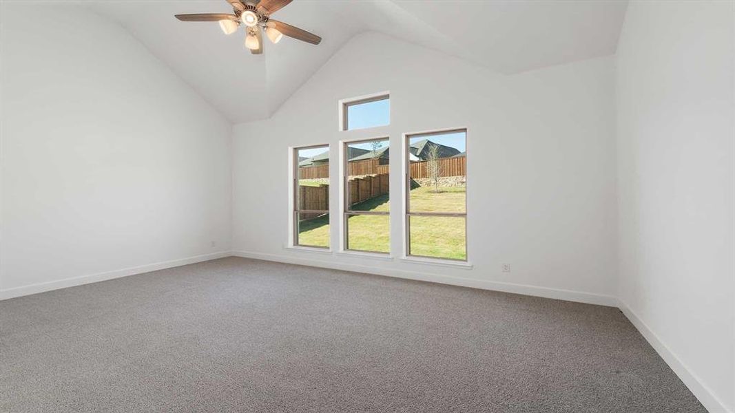 Carpeted empty room with high vaulted ceiling and ceiling fan