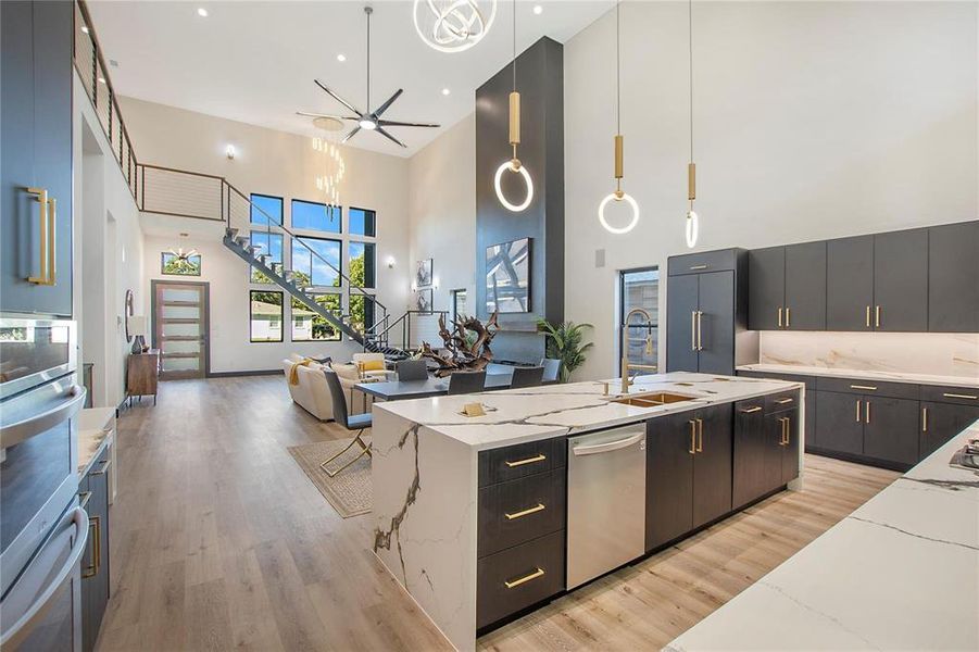 Kitchen with a kitchen island with sink, ceiling fan, light hardwood / wood-style floors, appliances with stainless steel finishes, and pendant lighting