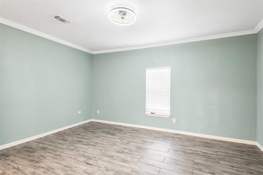 Unfurnished room featuring light wood-type flooring and crown molding