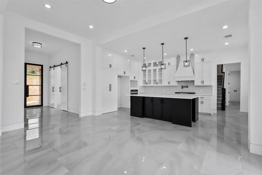 Kitchen featuring white cabinetry, a center island, custom exhaust hood, and light tile patterned flooring