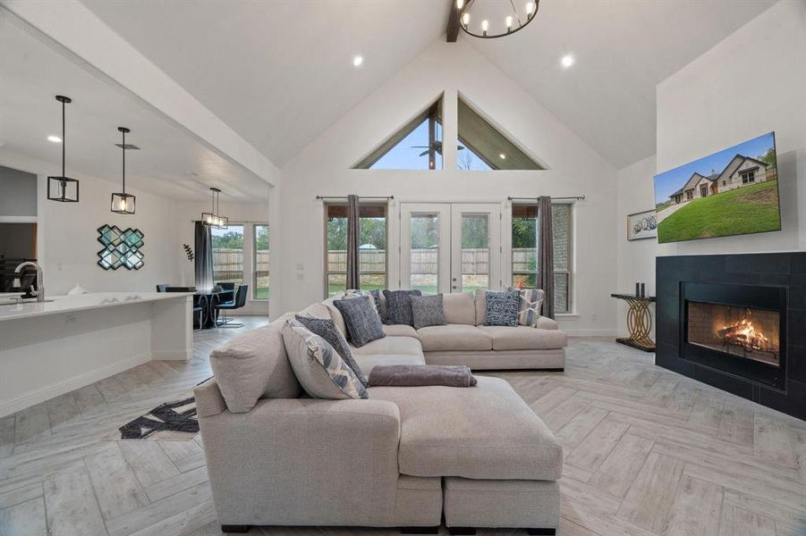 Living room featuring light parquet floors, a tile fireplace, high vaulted ceiling, and a wealth of natural light