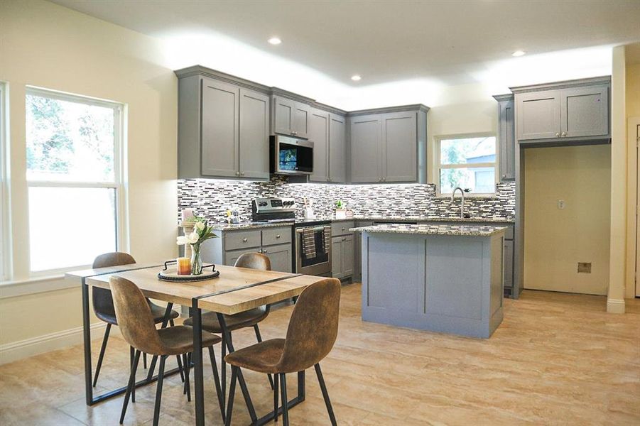 Kitchen with a center island, light hardwood / wood-style flooring, gray cabinetry, and stainless steel appliances