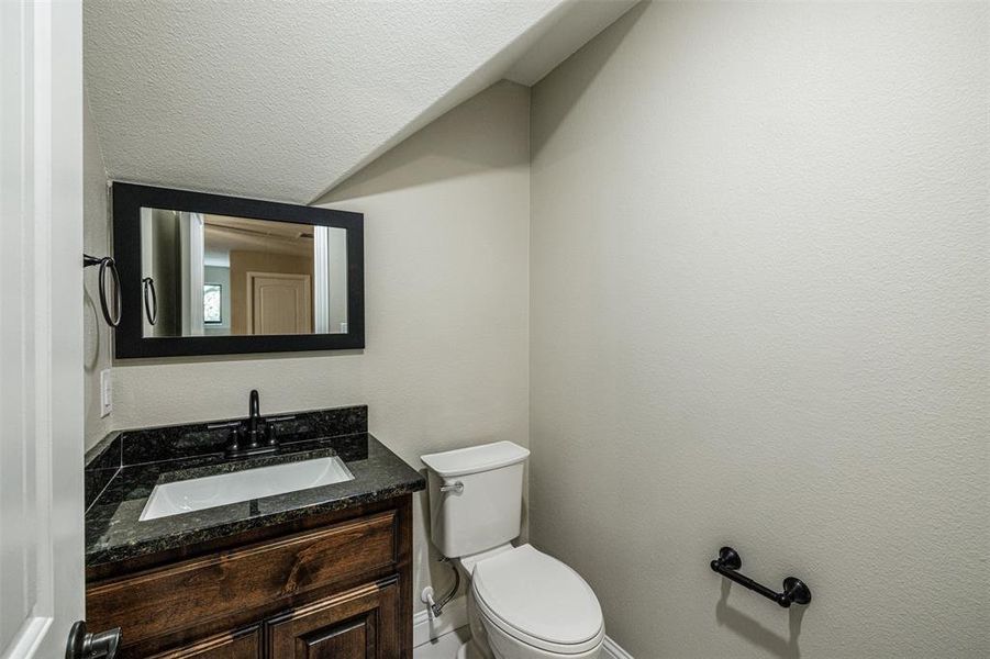 Bathroom featuring a textured ceiling, vanity, and toilet