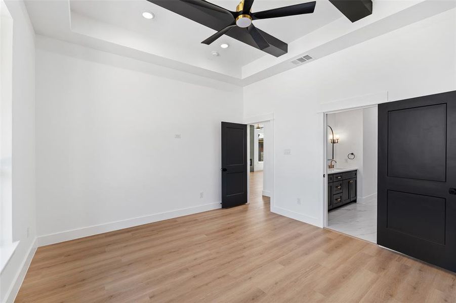 Spare room featuring ceiling fan, a raised ceiling, a towering ceiling, and light hardwood / wood-style floors