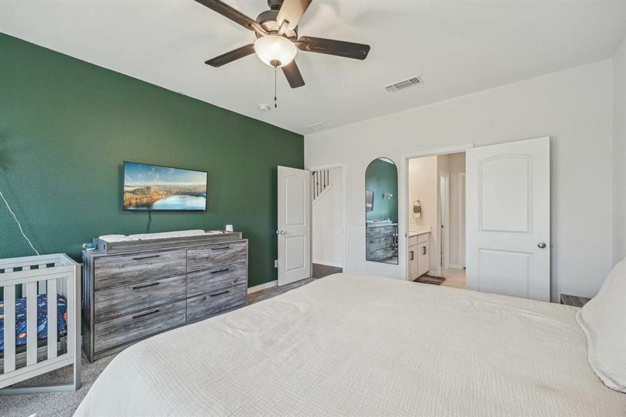 Carpeted bedroom featuring ensuite bath and ceiling fan