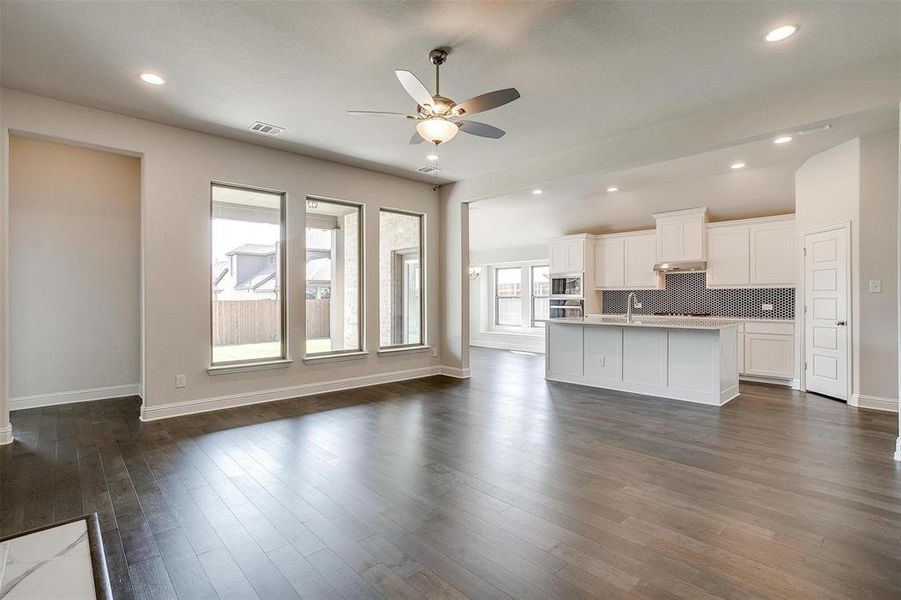 Unfurnished living room with dark wood-type flooring, ceiling fan, and sink