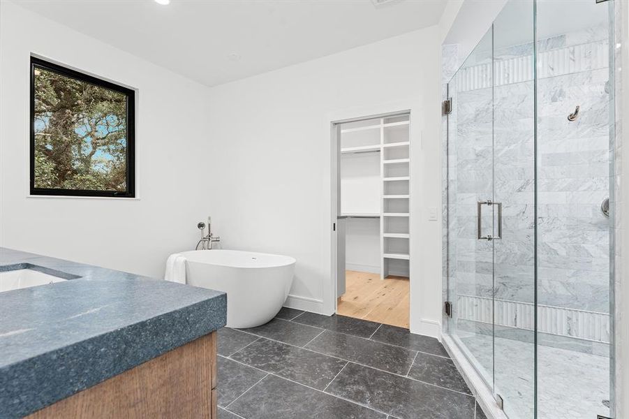 The primary bathroom is an exercise in calm - natural soapstone, limestones, woods and marbles in neutral tones lend a spa feel to this luxurious escape.