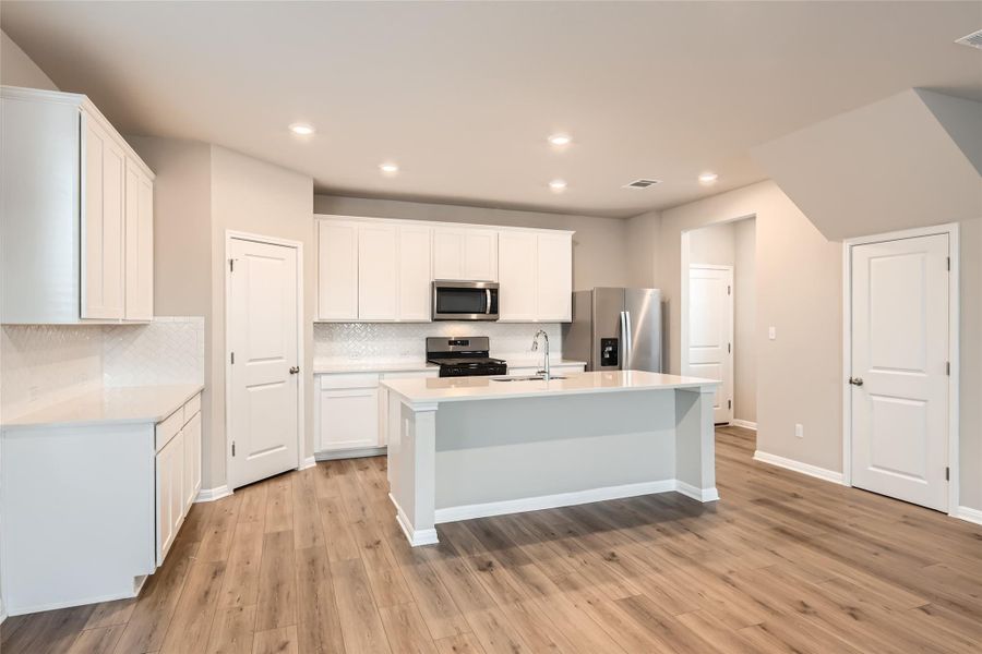 The interior features the sought-after "Divine" color scheme with light engineered vinyl plank floors, quartz countertops, Barrett Linen cabinetry, and herringbone tile backsplash.