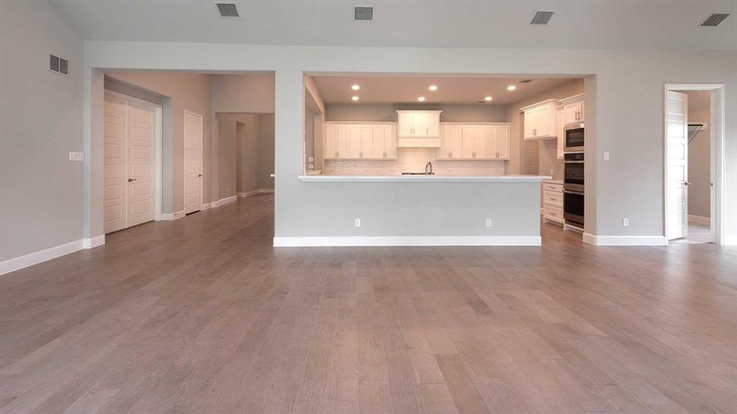 Kitchen with stainless steel appliances, hardwood / wood-style floors, sink, kitchen peninsula, and white cabinetry