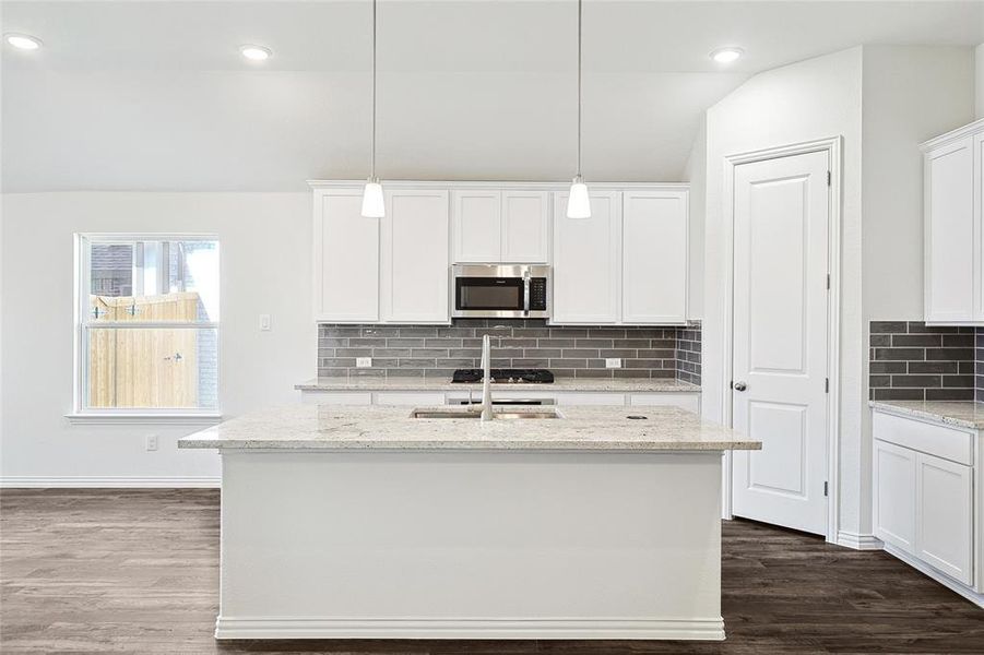 Kitchen with a kitchen island with sink, white cabinets, and dark hardwood / wood-style floors