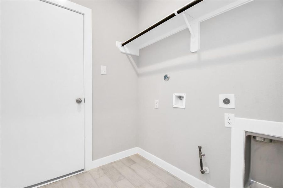 A spacious utility room with ample shelving for organization. It features connections for both gas and electric dryers, making it versatile and functional for all laundry needs. Sample photo of completed home with similar floor plan. Actual colors and selections may vary.