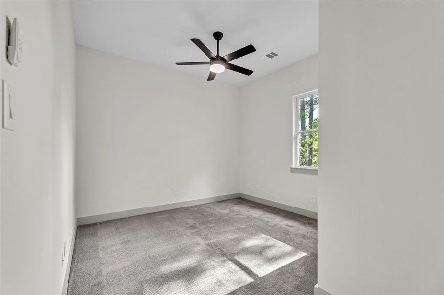 Bedroom with  gray carpet, ceiling fan and a nice view of the backyard trees.