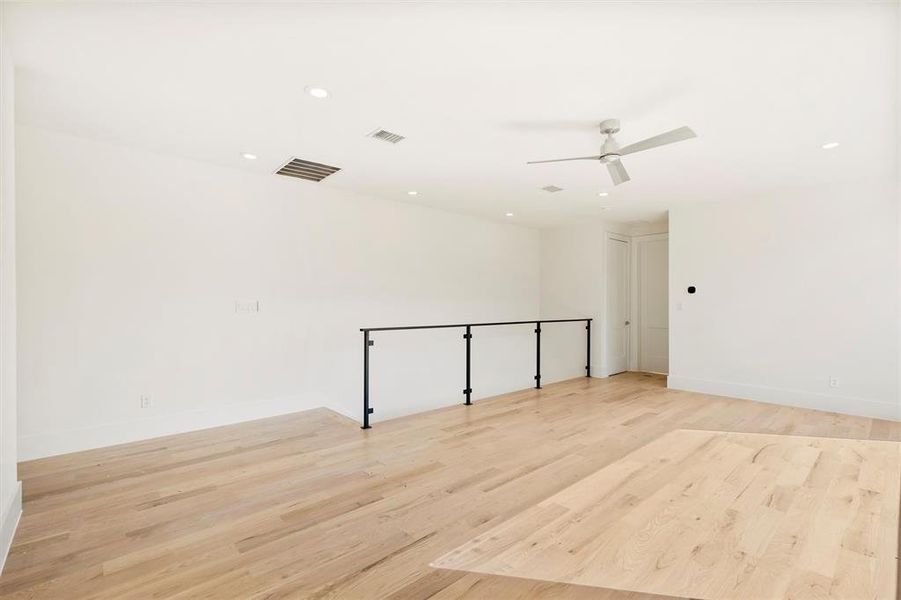 Empty room with ceiling fan and light hardwood / wood-style floors