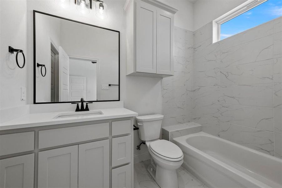 Full bathroom with tiled shower / bath, tile flooring, toilet, and large vanity