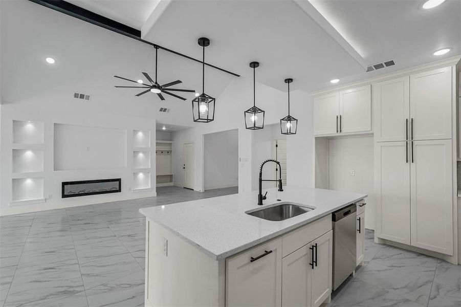 Kitchen featuring light stone counters, sink, white cabinets, ceiling fan, and stainless steel dishwasher