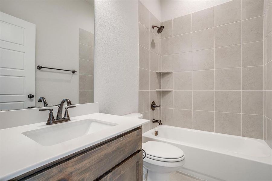 Full bathroom featuring tiled shower / bath combo, vanity, and toilet