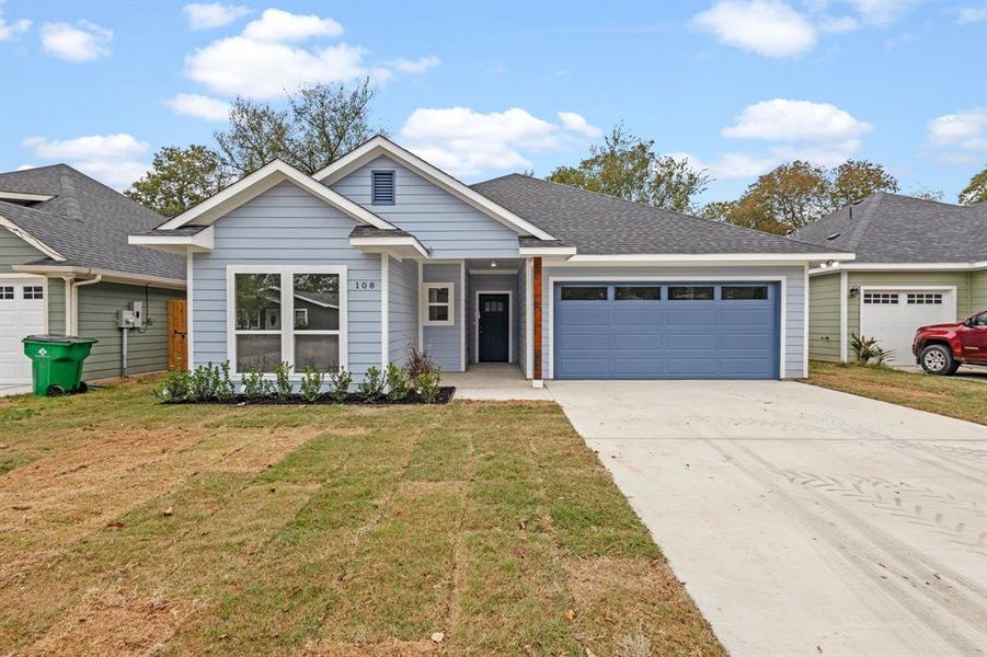 View of front of home with a front yard and a garage