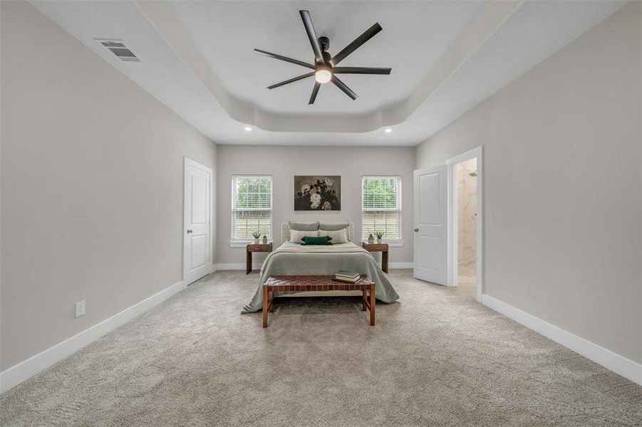 Master Bedroom with light carpet, a raised ceiling, ensuite bathroom, and ceiling fan