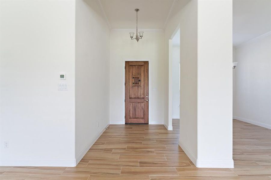 Entryway featuring an inviting chandelier and crown molding