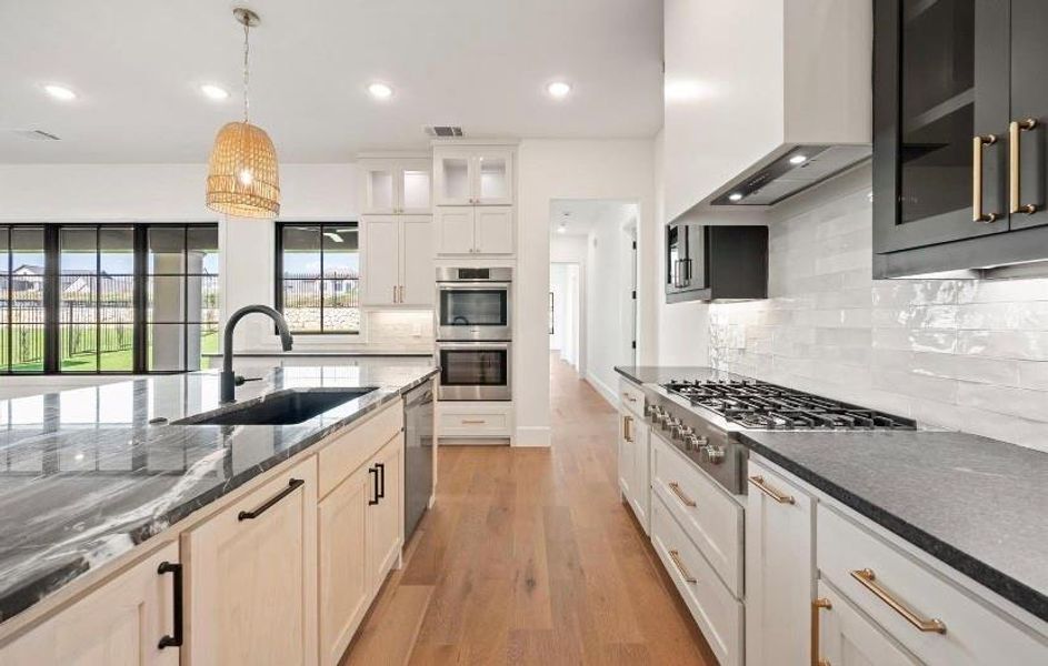 Kitchen featuring light wood-type flooring, tasteful backsplash, sink, wall chimney exhaust hood, and appliances with stainless steel finishes