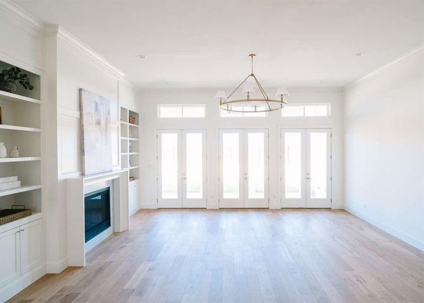 Unfurnished living room featuring light wood-type flooring, a chandelier, and a healthy amount of sunlight