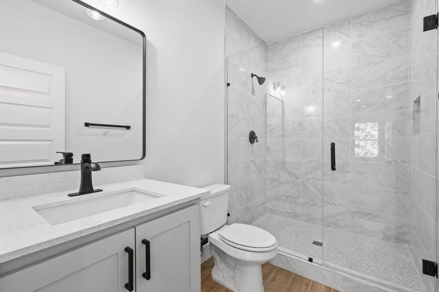 Bathroom with a shower with door, vanity, toilet, and hardwood / wood-style floors