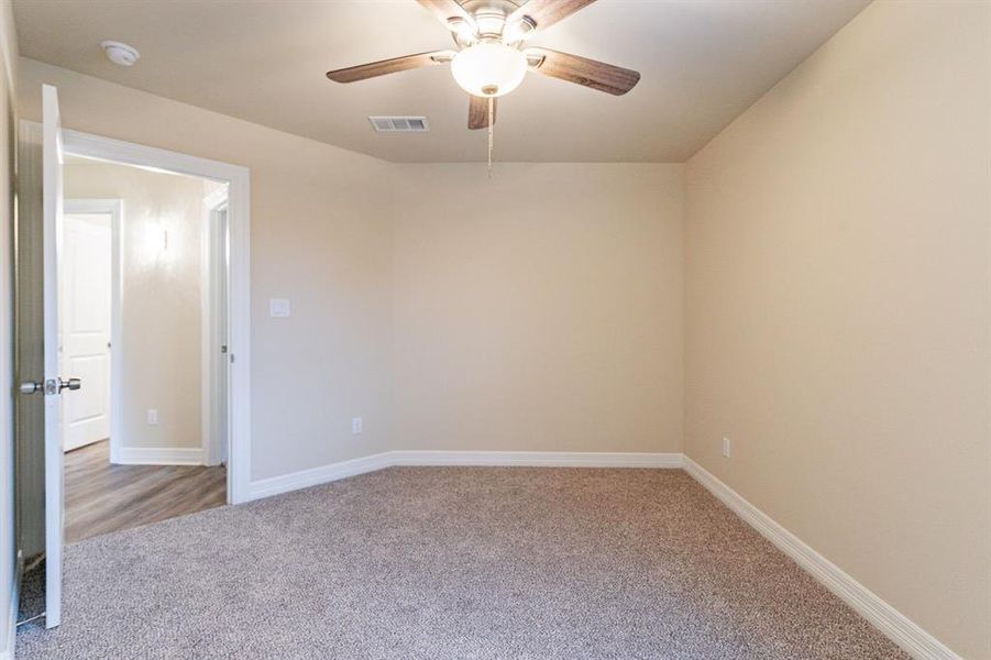 Empty room featuring ceiling fan and light carpet