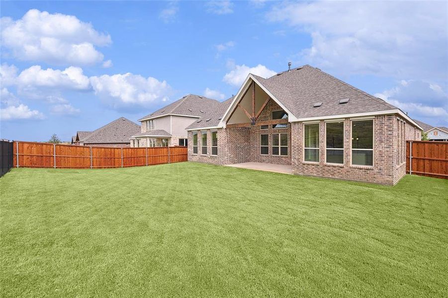 Rear view of house featuring a patio and a lawn