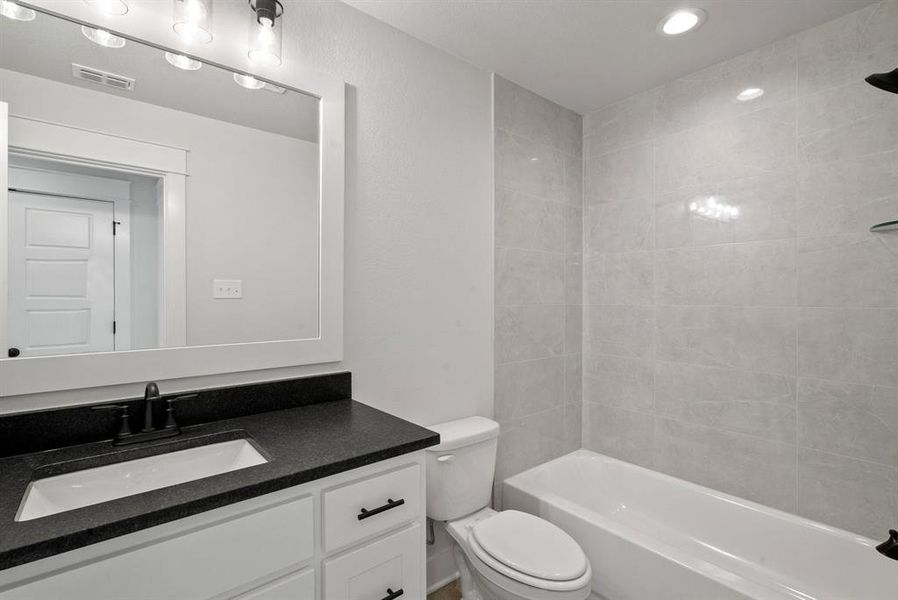 Full bathroom with vanity, toilet, and tiled shower / bath combo