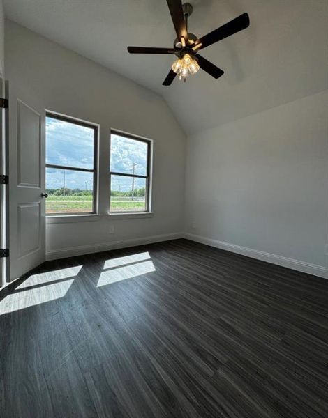 Additional living space featuring lofted ceiling, dark wood-type flooring, and ceiling fan