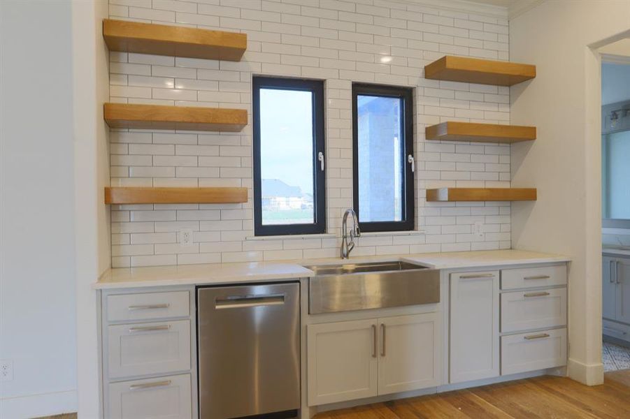 Kitchen featuring light hardwood / wood-style flooring, sink, stainless steel dishwasher, decorative backsplash, and ornamental molding