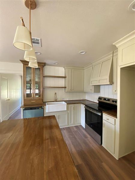 Kitchen with dishwashing machine, pendant lighting, stainless steel range oven, dark hardwood / wood-style floors, and extractor fan