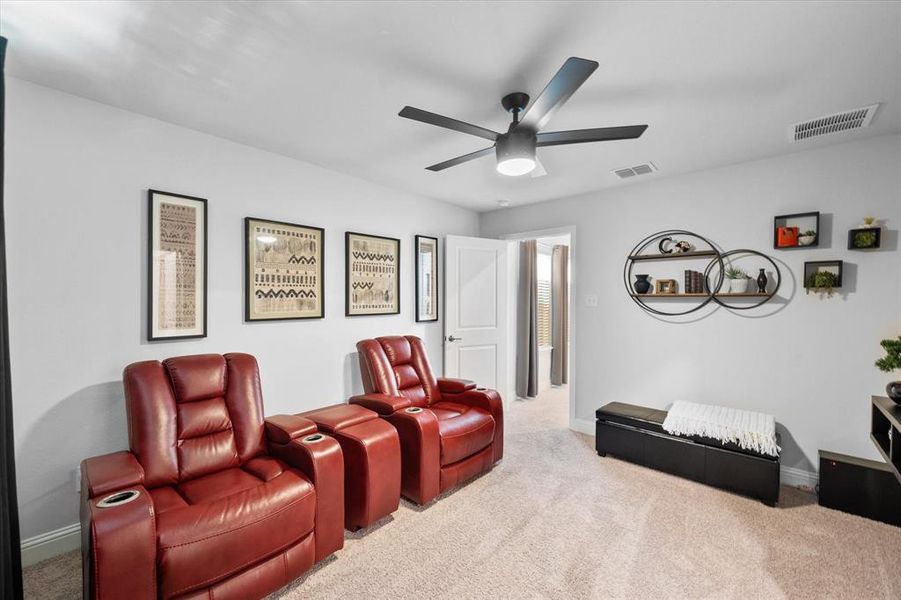 Home theater room with ceiling fan and carpet floors