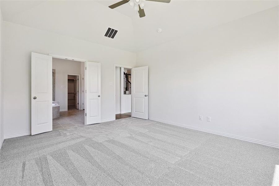 Unfurnished bedroom featuring high vaulted ceiling, ceiling fan, connected bathroom, and light colored carpet