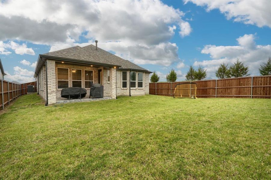 Rear view of property featuring cooling unit, a patio, and a yard