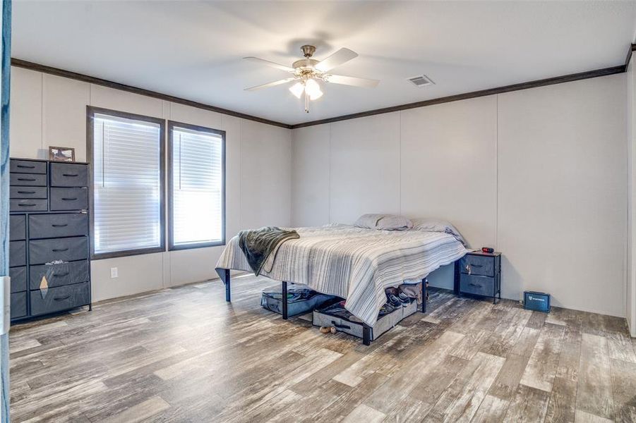 Bedroom with light wood-type flooring, ceiling fan, and crown molding