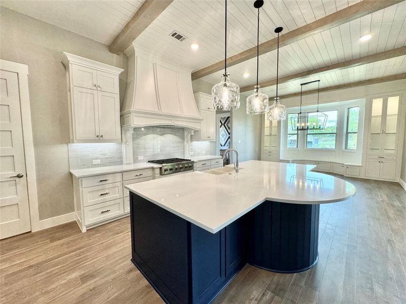 Kitchen with decorative light fixtures, light hardwood / wood-style floors, white cabinetry, and beam ceiling