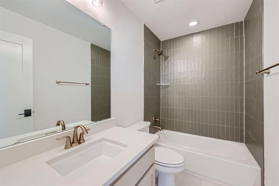 Full bathroom featuring tiled shower / bath combo, vanity, and toilet