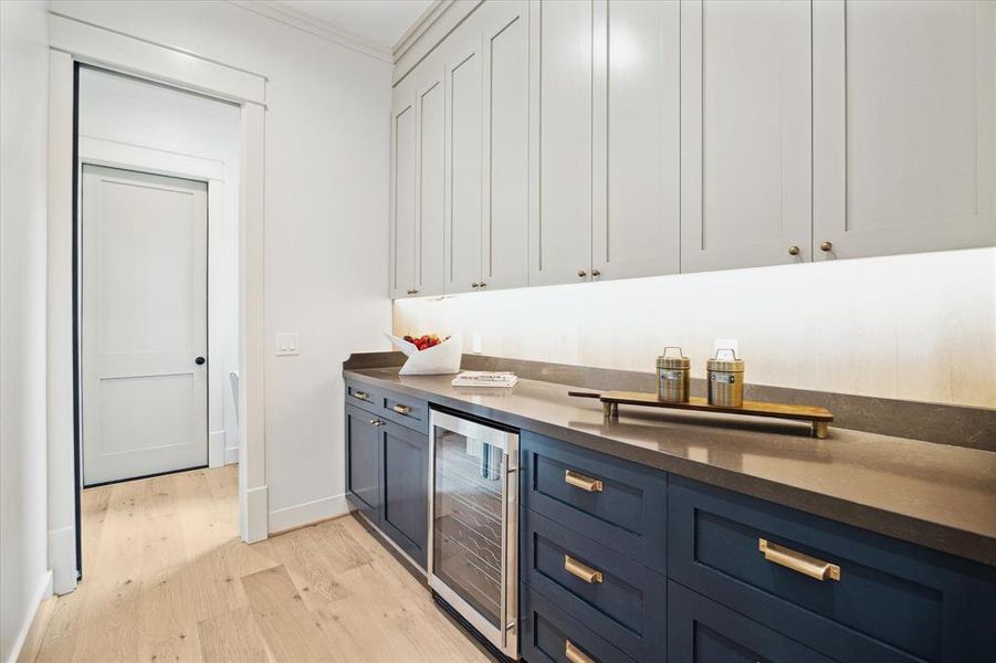 The scullery off the kitchen was built with busy lifestyles in mind! This separate prep area features quartz counters, beverage refrigerator and extra cabinet and drawer space that will come in handy for holiday entertaining. To the left is a huge walk-in pantry with a nook equipped with plumbing/electrical for a 2nd refrigerator and past the pocket door is a planning center and mudroom.