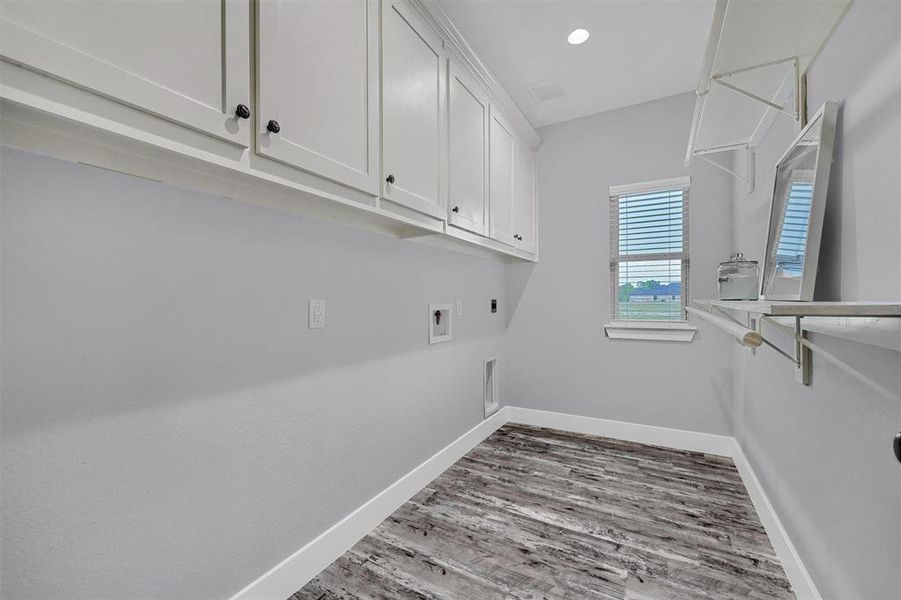 Washroom with washer hookup, hookup for an electric dryer, cabinets, gas dryer hookup, and hardwood / wood-style floors