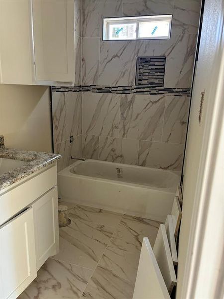 Bathroom featuring tile patterned floors, vanity, and tiled shower / bath