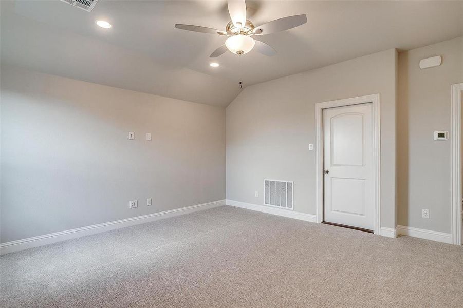 Empty room featuring vaulted ceiling, ceiling fan, and carpet flooring