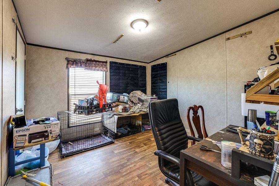 Office space featuring ornamental molding, light wood-type flooring, and a textured ceiling