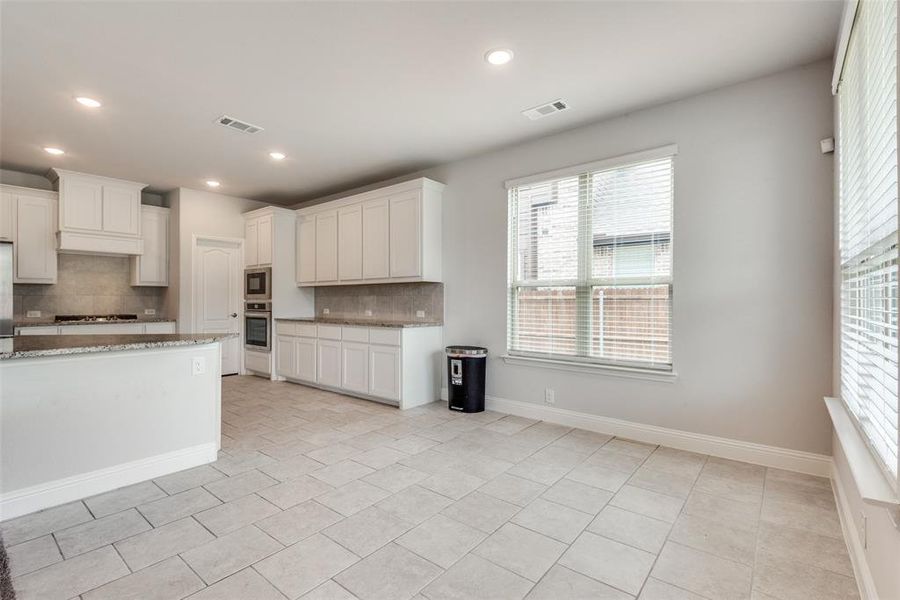 Kitchen featuring white cabinetry, oven, and tasteful backsplash