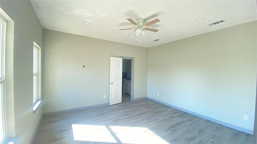 Unfurnished room featuring plenty of natural light, ceiling fan, and hardwood / wood-style flooring