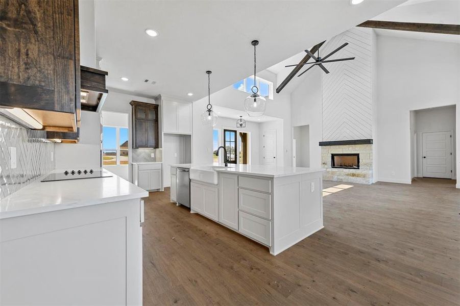 Kitchen featuring hanging light fixtures, a fireplace, white cabinets, hardwood / wood-style floors, and backsplash